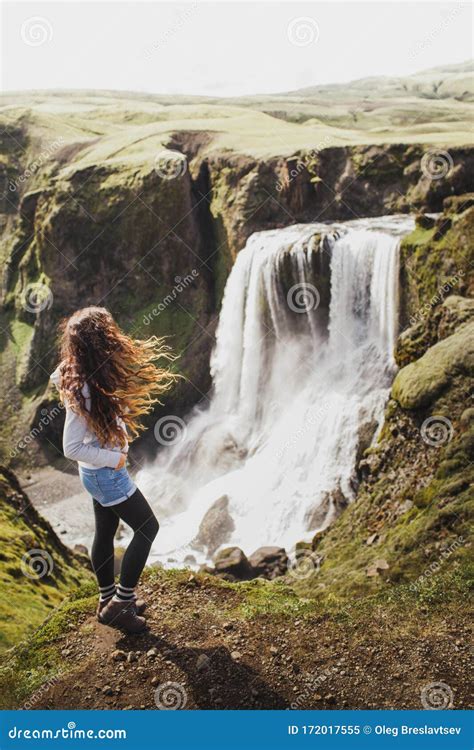 Curly Woman Looking On Fagrifoss Waterfall In Iceland View From The