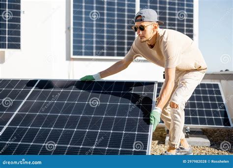 Man Installing Solar Panels On The Roof Of His House Stock Photo