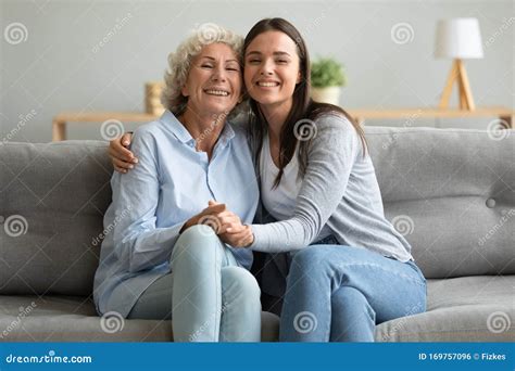 Portrait Happy Grandmother And Granddaughter Hugging Sitting On Couch