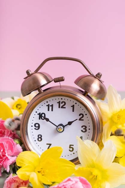 Premium Photo | Alarm clock with spring flowers Spring time daylight savings concept spring forward