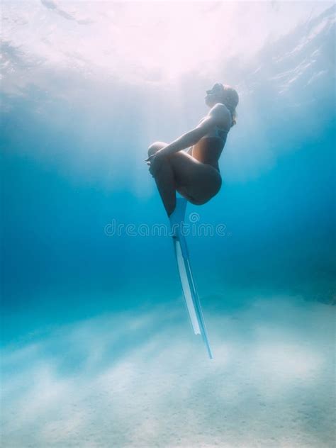 Female Freediver In Bikini Posing Over Sandy Bottom With White Fins