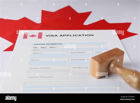 Immigration To Canada Visa Application Form And Wooden Stamp On Flag