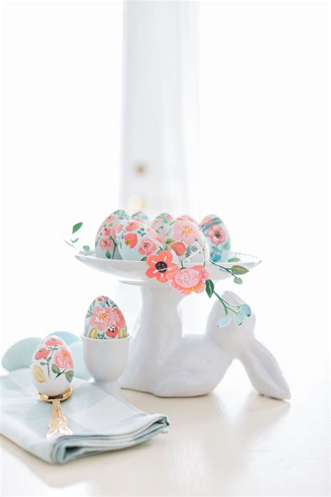 An Egg Decorated With Flowers Sits On A Plate Next To Other Eggs And