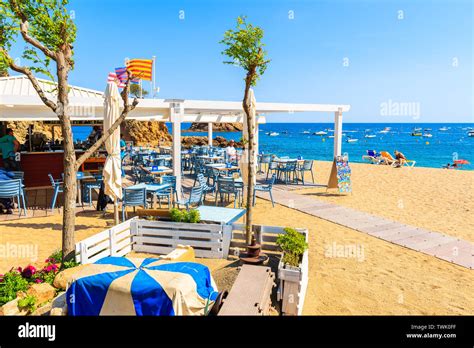 TOSSA DE MAR, SPAIN - JUN 3, 2019: People dining in restaurant on sandy ...