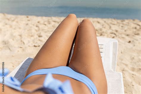 The Legs Of A Beautiful Curvy Blonde With Long Hair In A Blue Swimsuit Gets A Tan While Lying In