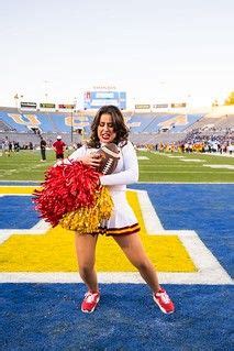 A Cheerleader On The Sidelines At A Football Game With Her Pom Poms