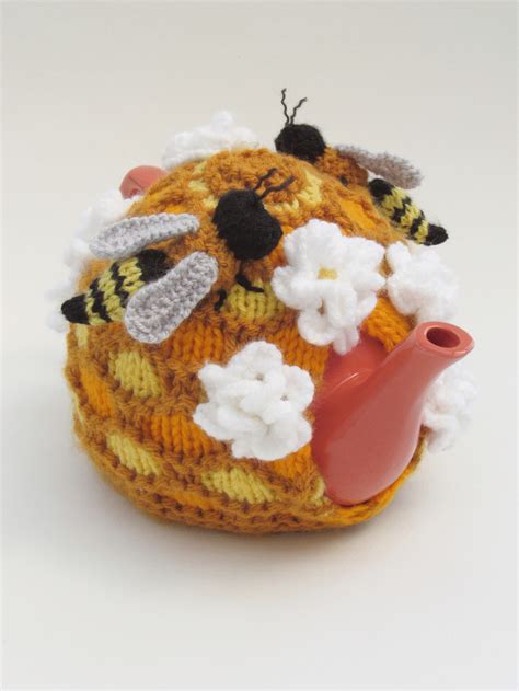 A Knitted Tea Cosy With Bees And Flowers On It