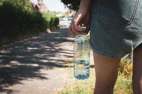 Chica Sosteniendo Una Botella De Agua En El Parque Foto Premium