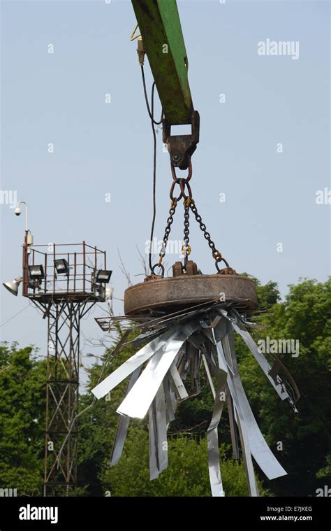 magnetic grab on crane lifting metal at scrapyard uk Stock Photo - Alamy