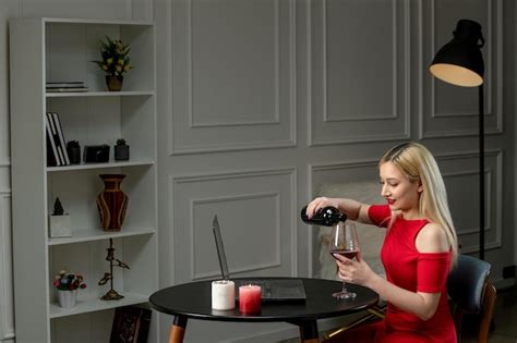 Amour virtuel jolie fille blonde en robe rouge à distance date avec des bougies versant du vin