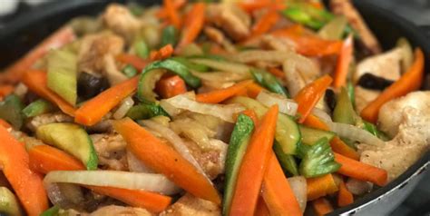 A Pan Filled With Chicken And Vegetables On Top Of A Stove