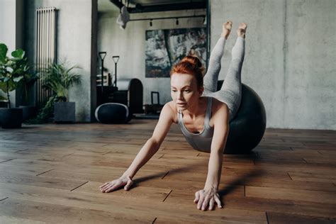 Athletic slender lady with red hair performing streching exercises on