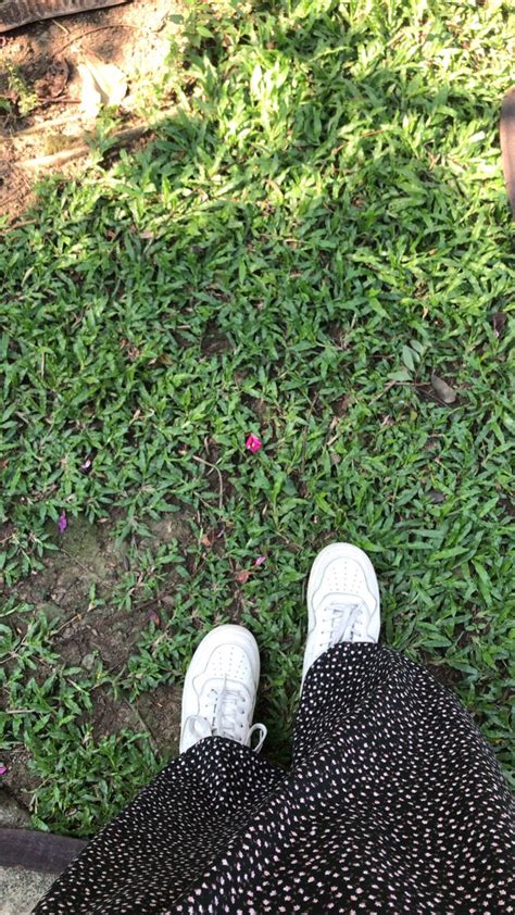 A Person With Their Feet Up On The Ground Next To Some Grass And A Red