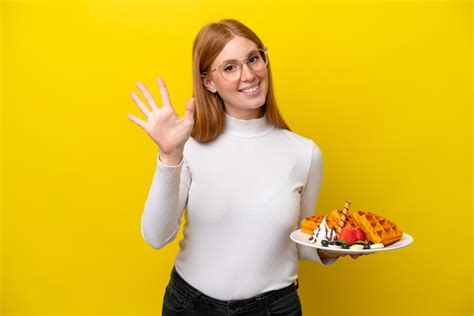 Mulher Jovem Ruiva Segurando Waffles Isolados Em Fundo Amarelo Contando