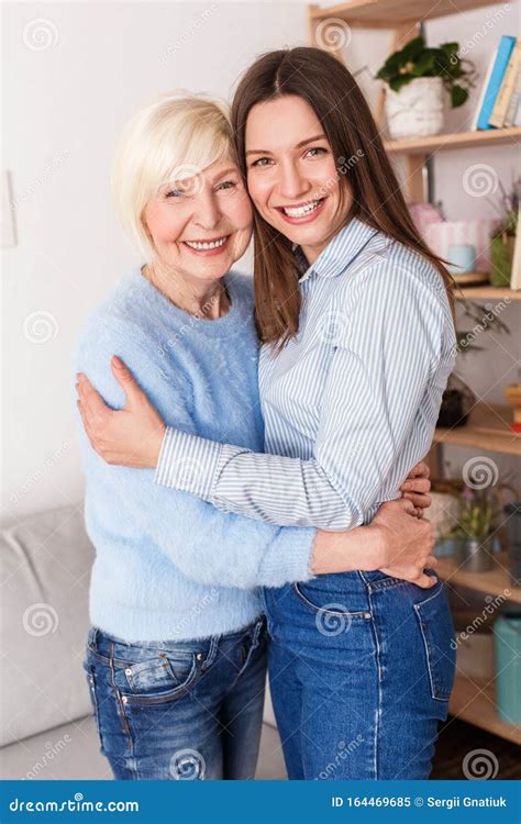 Adult Daughter And Her Retirement Mother Hugging At Home Stock Image