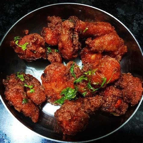 Some Fried Food In A Metal Bowl On A Black Counter Top With Green Leafy