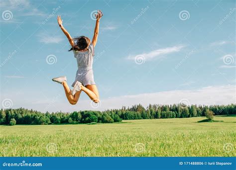 Happy Woman Jumping In Green Field Against Blue Sky Stock Photo Image