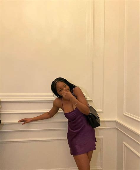 A Woman In A Purple Dress Leaning Against A Wall With Her Hand On Her Face