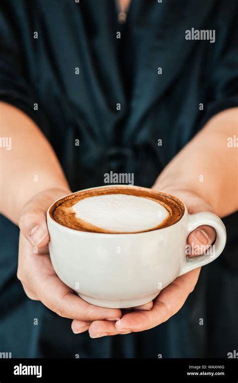 Female Hands Holding Cup Of Beautiful Hot Coffee Capuccino With Nice Milk Form On Top Close Up