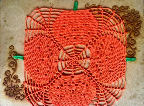 An Orange Crocheted Doily Is On The Ground