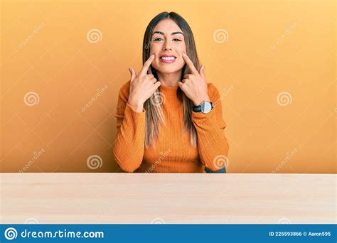 Young Hispanic Woman Wearing Casual Clothes Sitting On The Table