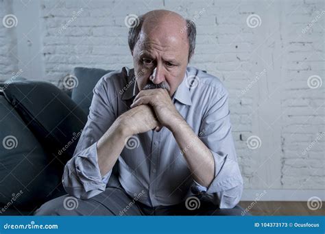 Portrait Of Senior Mature Old Man On His 60s At Home Couch Alone Feeling Sad And Worried