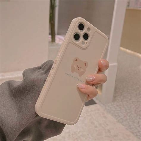 A Woman Holding Up Her Phone Case With A Bear Sticker On It