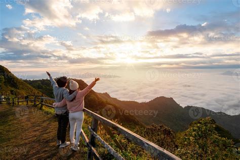 Young couple travelers looking at the sunrise and the sea of mist on
