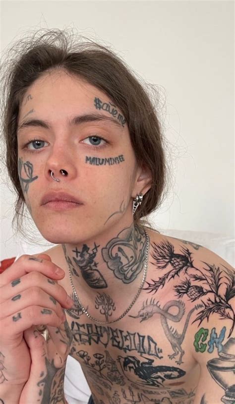 A Woman With Tattoos And Piercings On Her Chest Looking At The Camera