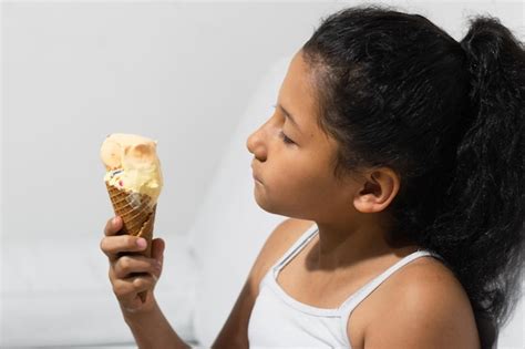 Niña latina de piel morena sosteniendo un cono de helado en la mano