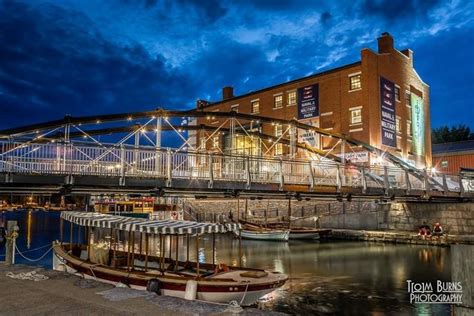 a boat is docked in the water near a bridge and buildings at night with ...