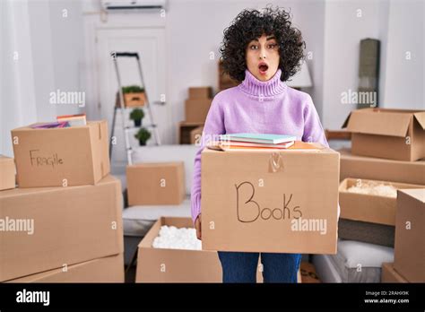 Jeune femme brunette avec cheveux bouclés se déplaçant à une nouvelle maison tenant boîte en