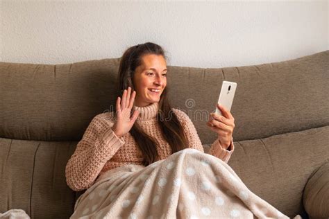 Woman Lying On The Sofa And Covered With A Blanket Watches Television