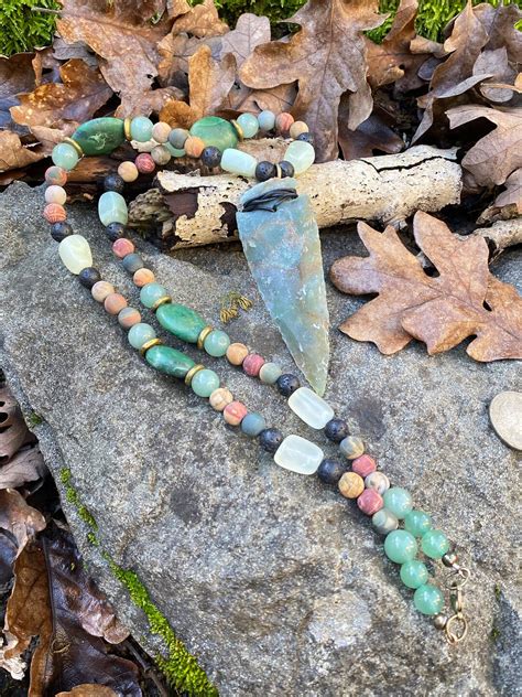 Stone Arrowhead Pendant Wrapped With Leather And Hanging From A Strand