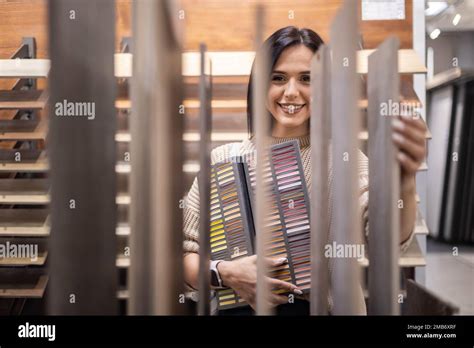 Happy Brunette Female Interior Designer Choosing Flooring Tile Color Texture Samples At Store