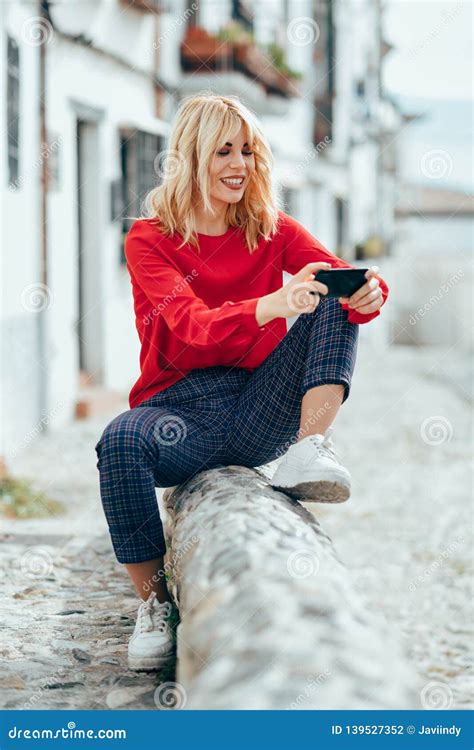 Jeune Femme Blonde S Asseyant Sur Le Fond Urbain Chose Utile Smartphone Photo Stock Image Du