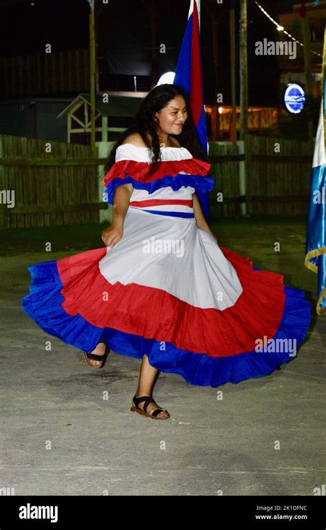 A young woman, dancing, wearing a dress with the colors of the Belizean flag, at the festivities ...