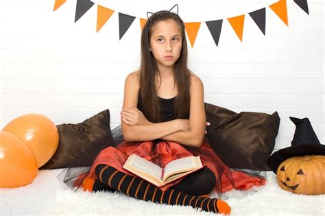 Premium Photo Pensive Brunette Girl In Witch Costume With Witchcraft Book Celebrating