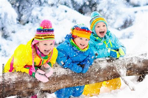 Kids Playing In Snow Children Play Outdoors In Winter Snowfall Stock