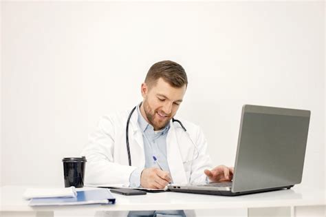 Free Photo Caucasian Doctor Sitting At Workplace And Using Laptop