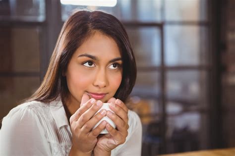 Hermosa mujer tomando un café y mirando lejos Foto Premium