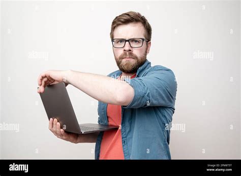 Serious Concentrated Bearded Man With Glasses Holds A Laptop In Hands