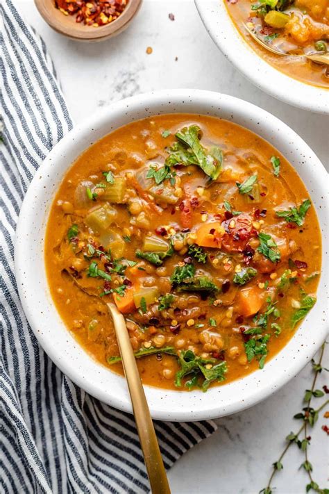 Two White Bowls Filled With Soup On Top Of A Table Next To Spoons And