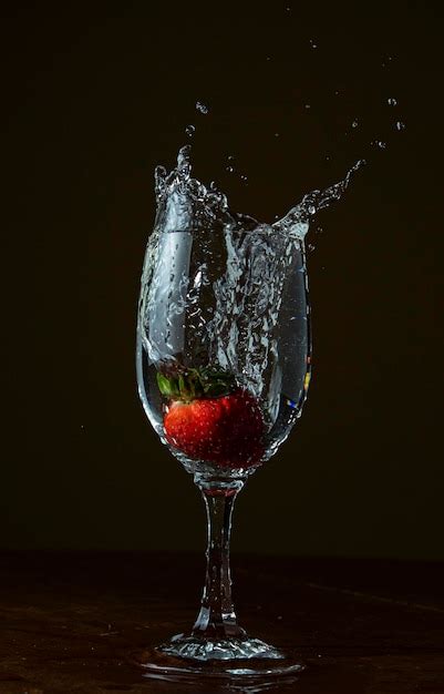 Premium Photo A Strawberry Is Being Dropped Into A Glass Of Water