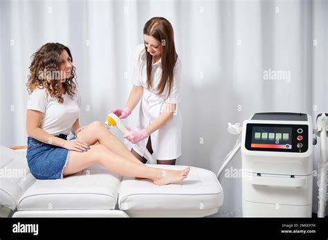 Young cosmetologist performing procedure of laser removal of unwanted ...