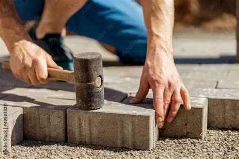 Young man laying gray concrete paving slabs in house courtyard on ...