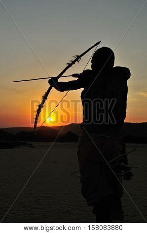 Man From Hadza Tribe Hunting With Traditional Bow And Arrow As They Did