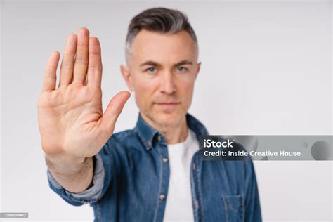 Handsome Caucasian Mature Man Showing Stop Sign Isolated Over White