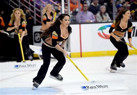 Two Women In Black And Orange Outfits Skating On Ice