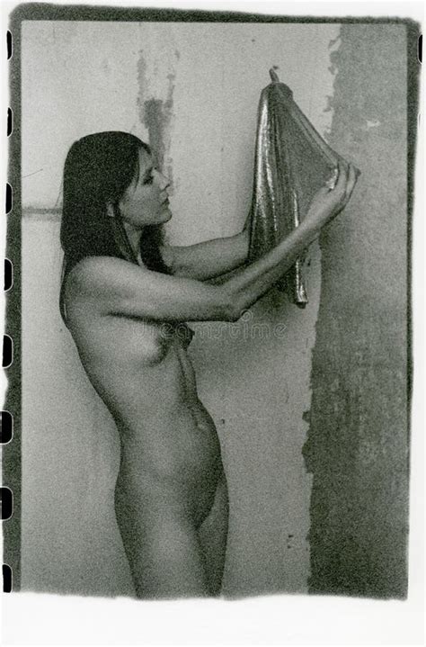 Eine Schöne Nackte Brunette Hält Sich in Den Armen Und Untersucht Glänzende Kleider Stockfoto